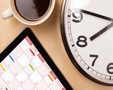 Tablet pc showing calendar on screen with a cup of coffee on a d